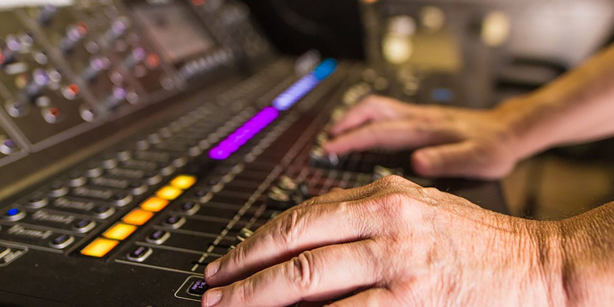 Cinematic Live Sports Broadcasting Uses Film Techniques to Captivate Fans 9 An audio engineer fine-tunes sound levels and effects on a mixing board, crafting an immersive audio experience for a live sports broadcast.