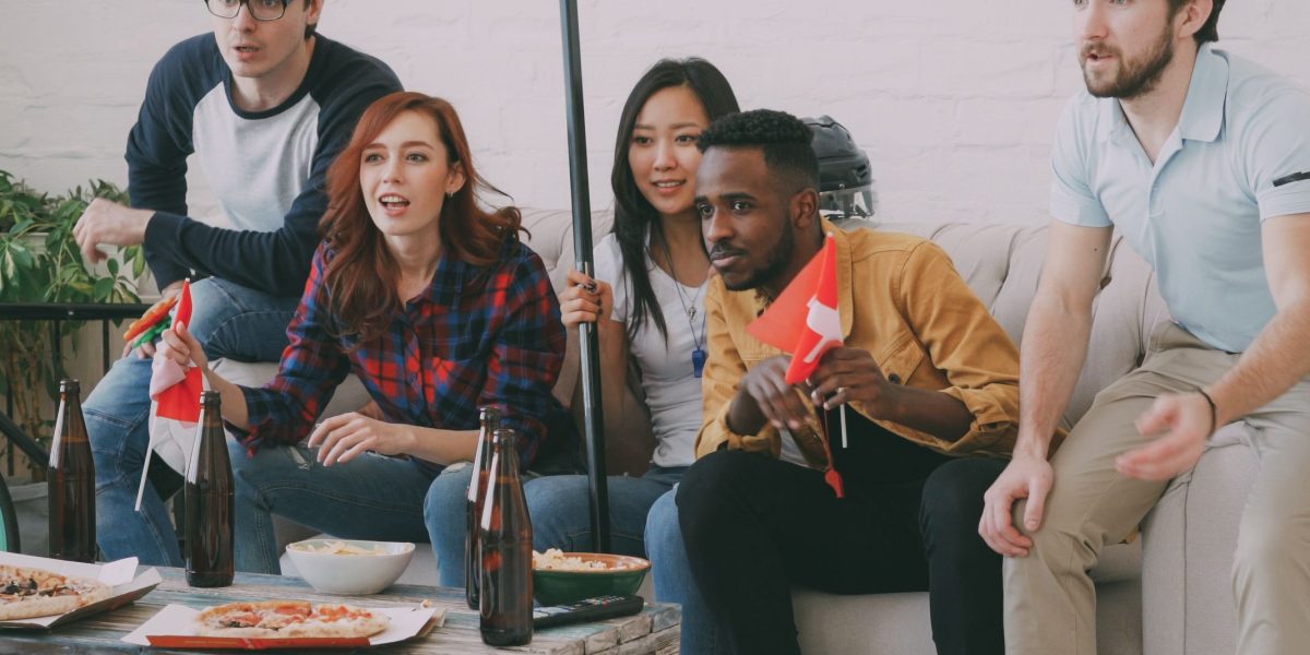 Friends and family gather to watch a live sports game, sharing excitement and cheering for their favorite team.