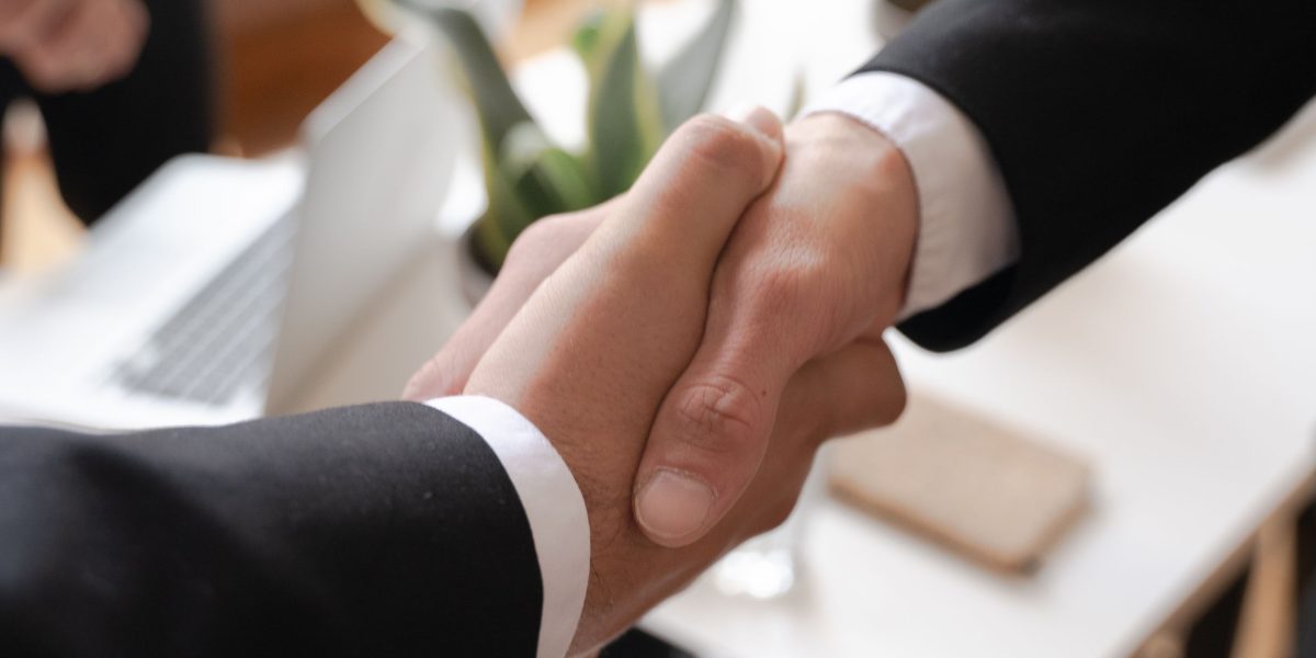 Master Regional and Collegiate Sports Broadcasting for Global Brands 5 Professionals shaking hands after a successful meeting, symbolizing the completion of a media rights negotiation or partnership agreement.