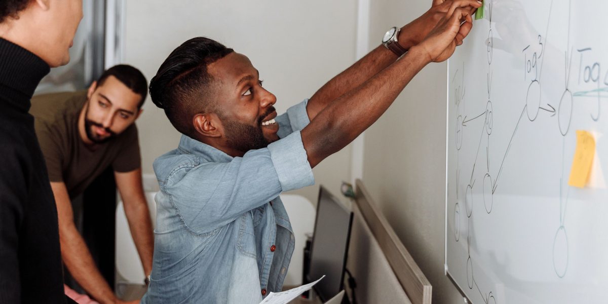 Mastering Global Sports Broadcasting for Worldwide Fan Engagement 2 A team of professionals collaborating and strategizing around a whiteboard, symbolizing the complex coordination required for global broadcasts.