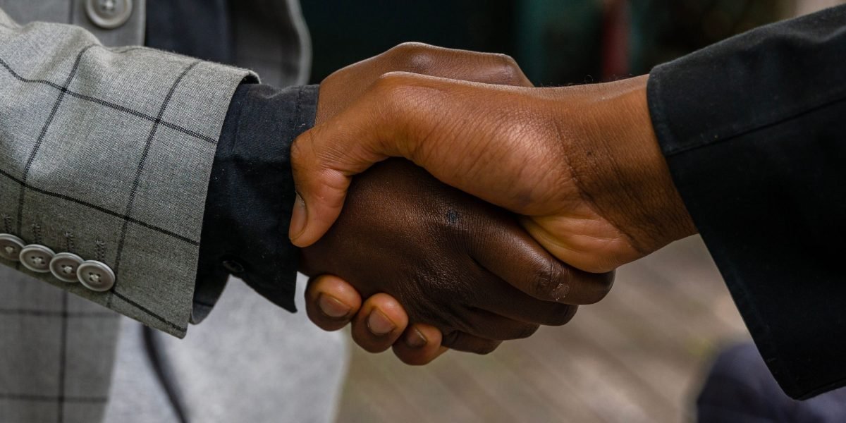 Choosing Live TV Channels and Streaming Platforms for Global Sports Broadcasting 10 Professionals finalizing a broadcast rights and platform partnership agreement with a handshake.